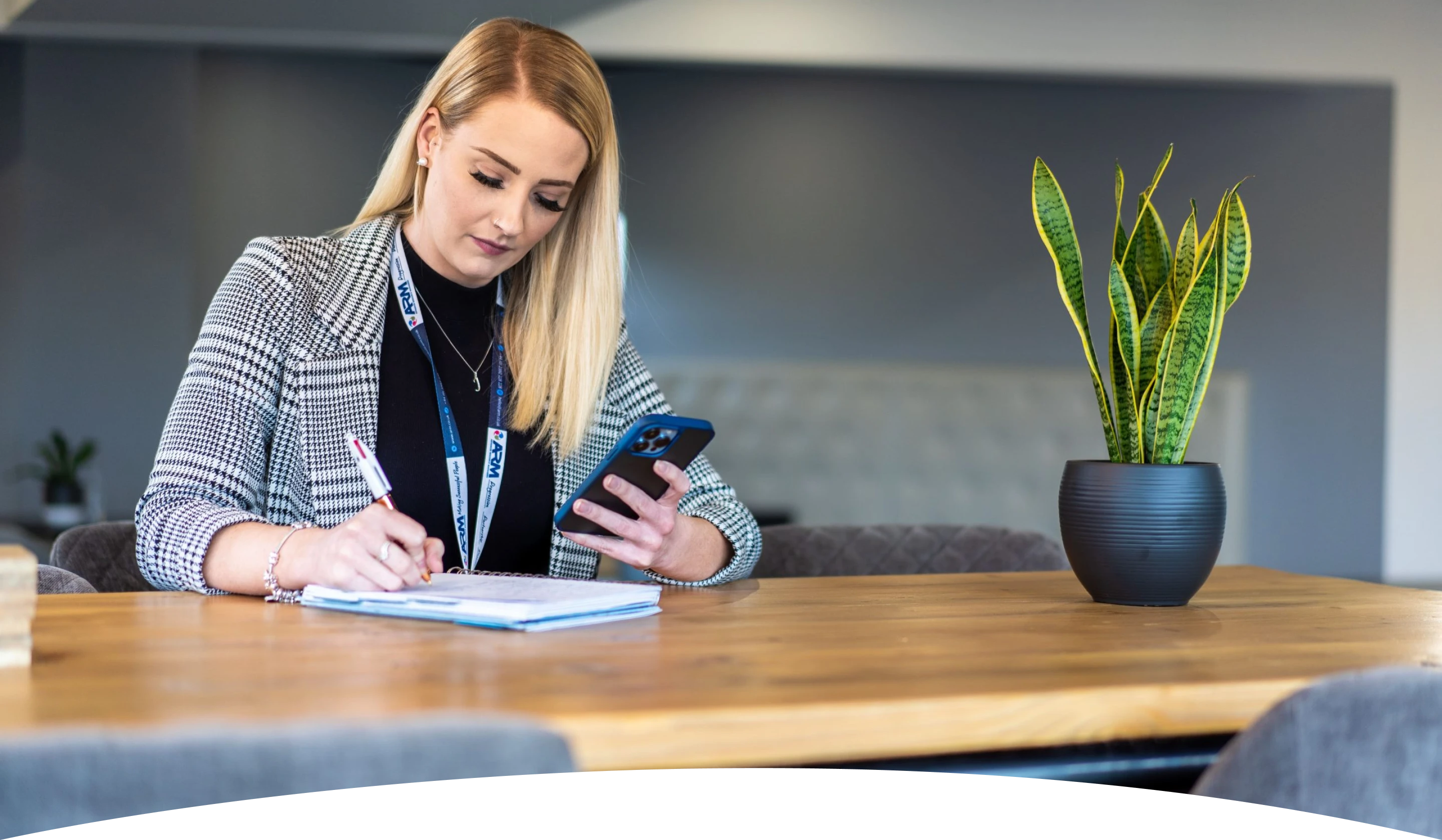 A female employee of ARM Recruitment sat a desk taking notes